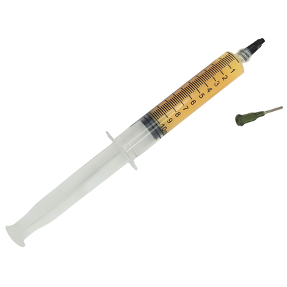 Syringe filled with yellow paste with black measurement markings and a separate dispensing tip on a white background