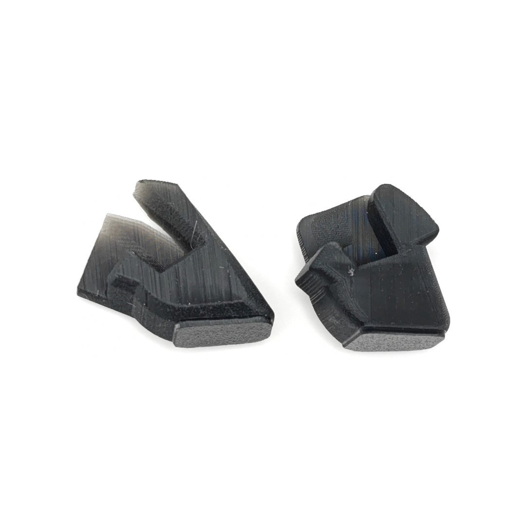 Two black plastic trigger pieces on a white background