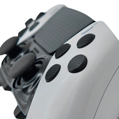 Close-up of a white and black controller with textured black face buttons on a transparent background