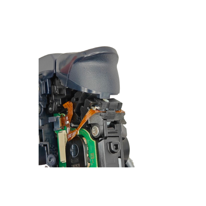 Close-up of the inside of a controller showing a gray trigger, black plastic housing, orange ribbon cable, green circuit board, and screw on a transparent background
