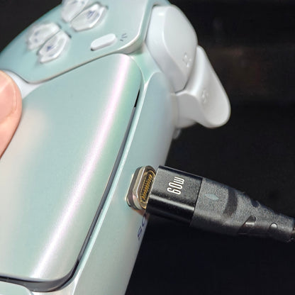 Close-up of a black magnetic charging cable connected to the top of a white iridescent controller